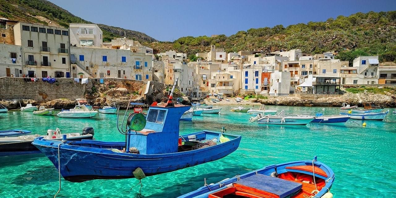 Porto di Levanzo con barche colorate e acque turchesi